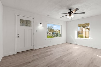 Foyer entrance with light wood-style floors, a textured ceiling, and a ceiling fan