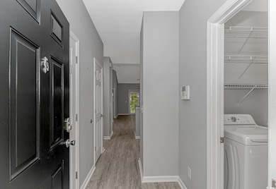 Laundry area with washer / clothes dryer, light wood-type flooring, and baseboards