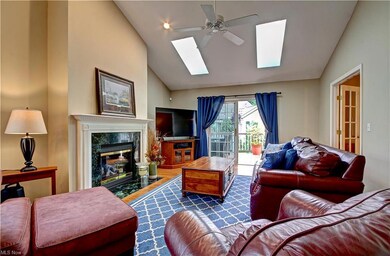 Hardwood floored living room with vaulted ceiling with skylight and a fireplace