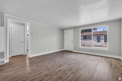 Unfurnished living room featuring wood finished floors, a heating unit, a textured ceiling, and wooden walls
