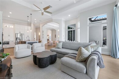 Living room with arched walkways, ornamental molding, recessed lighting, light wood finished floors, and ceiling fan