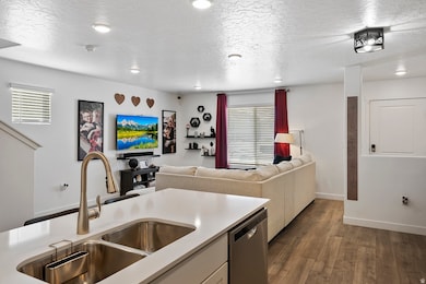 Kitchen featuring stainless steel dishwasher, dark wood finished floors, open floor plan, a textured ceiling, and white cabinets