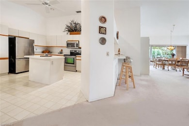 Kitchen with light countertops, stainless steel appliances, a kitchen breakfast bar, a kitchen island, and light carpet