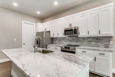 Kitchen with dark wood-type flooring, light stone countertops, and recessed lighting