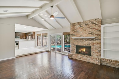 Unfurnished living room featuring dark wood-style flooring, a brick fireplace, a ceiling fan, and wood walls