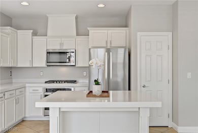 Kitchen featuring stainless steel appliances, light tile patterned floors, a center island, white cabinetry, and recessed lighting
