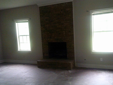Unfurnished living room with baseboards, a brick fireplace, and visible vents