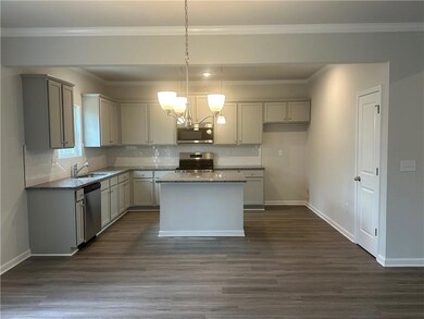 Kitchen with dark wood finished floors, stainless steel appliances, decorative backsplash, a chandelier, and baseboards