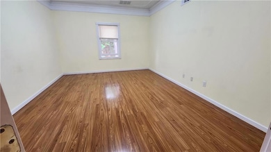 Unfurnished room featuring wood finished floors, crown molding, and baseboards