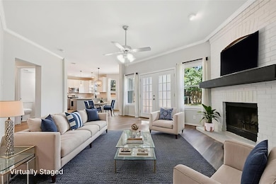 Living room featuring crown molding, wood finished floors, french doors, a ceiling fan, and a fireplace