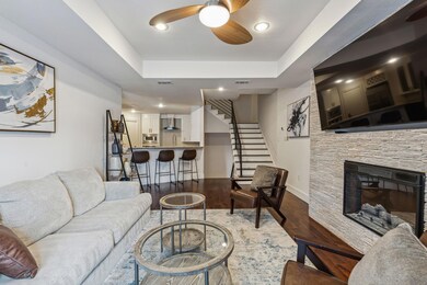 Living room with a raised ceiling, a stone firepla