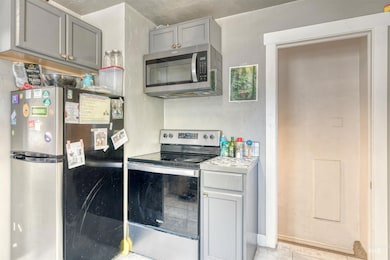 Kitchen featuring stainless steel appliances, gray cabinets, light countertops, and light tile patterned flooring