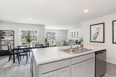 Kitchen with dishwasher, a kitchen island with sink, light wood finished floors, open floor plan, and light countertops