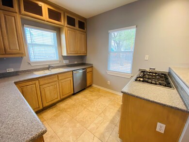 Kitchen with glass insert cabinets, stainless steel appliances, light tile patterned floors, and dark stone countertops