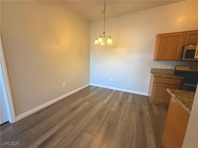 Unfurnished dining area featuring dark wood-style floors and a chandelier