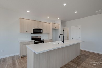 Kitchen with light brown cabinets, stainless steel appliances, recessed lighting, an island with sink, and light wood-type flooring