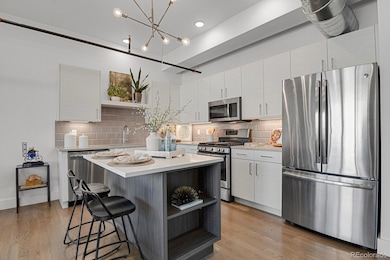 Gourmet kitchen impresses with a center island, quartz countertops, custom soft-close cabinetry, tile backsplash, and stainless steel appliances