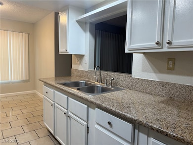 Kitchen featuring white cabinetry, light tile patterned flooring, and a textured ceiling