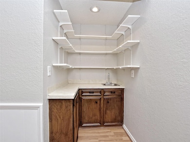 Indoor wet bar with a textured wall, light wood-s