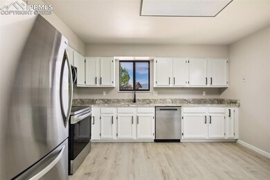 Kitchen featuring appliances with stainless steel finishes, a sink, light wood finished floors, and white cabinetry