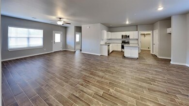 Kitchen with open floor plan, a center island, white cabinets, ceiling fan, and appliances with stainless steel finishes