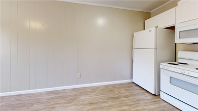 Kitchen featuring white appliances, light wood fin