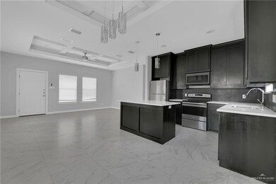 Kitchen featuring a kitchen island, appliances with stainless steel finishes, a tray ceiling, backsplash, and coffered ceiling
