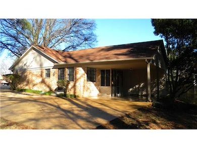 Carport with wrap-around driveway and parking pad.