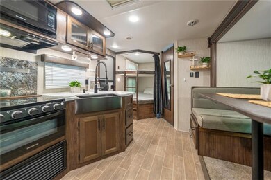 Kitchen featuring a sink, black appliances, light countertops, and light wood-style flooring