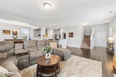 Living area featuring stairs, dark wood-type flooring, visible vents, and baseboards