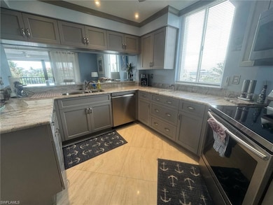 Kitchen with a sink, gray cabinetry, light stone c