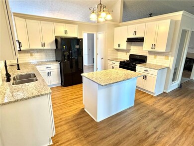 Kitchen with black appliances, white cabinets, and tasteful backsplash