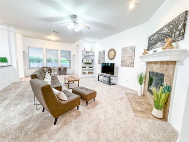 Carpeted living area with a tile fireplace, ceili