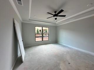 Empty room featuring a tray ceiling, ornamental molding, and a ceiling fan