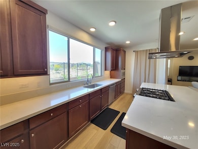 Kitchen with a sink, island range hood, light wood