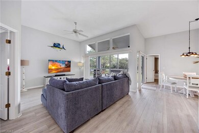 Living room featuring ceiling fan, a towering ceiling, and light hardwood / wood-style floors