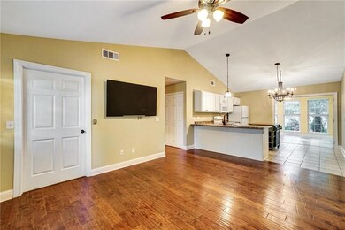 Unfurnished living room featuring ceiling fan, a chandelier, vaulted ceiling, and wood-type flooring