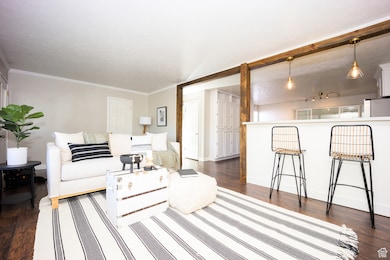 Living area featuring dark wood-style flooring and crown molding. Home is now vacant - these photos are provided to envision the room decorated.
