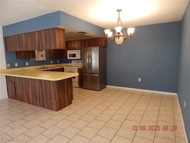 Kitchen featuring white appliances, light countertops, a peninsula, and light tile patterned floors
