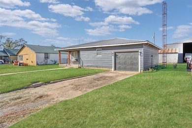 View of front of house featuring driveway, a metal roof, a garage, and a front yard