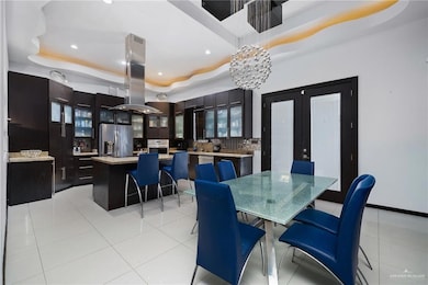 Dining room featuring a raised ceiling, light tile patterned floors, recessed lighting, and french doors