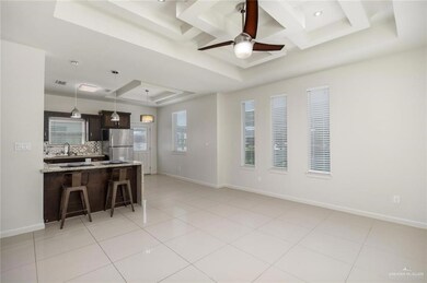 Kitchen featuring a breakfast bar area, decorative light fixtures, stainless steel refrigerator, a tray ceiling, and ceiling fan