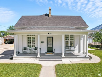 View of front of house with a porch, roof with shingles, a chimney, and brick siding