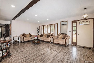 Living area featuring dark wood-style floors, beamed ceiling, and recessed lighting