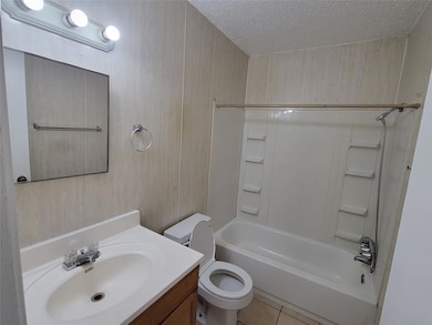 Bathroom featuring a textured ceiling, vanity, toi