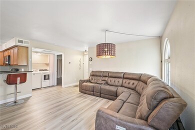 Living room with washing machine and clothes dryer and light wood-style floors