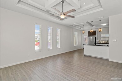 Unfurnished living room featuring coffered ceiling, ceiling fan, and a tray ceiling