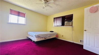 Bedroom with carpet floors, a textured ceiling, baseboards, ceiling fan, and cooling unit