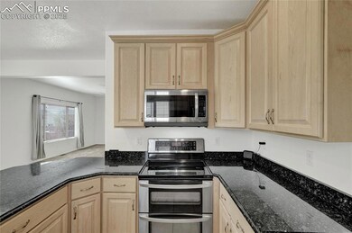 Kitchen featuring appliances with stainless steel finishes, light brown cabinetry, and dark stone counters