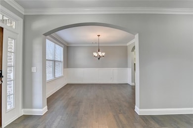 Entryway featuring crown molding, arched walkways, a chandelier, and dark wood finished floors